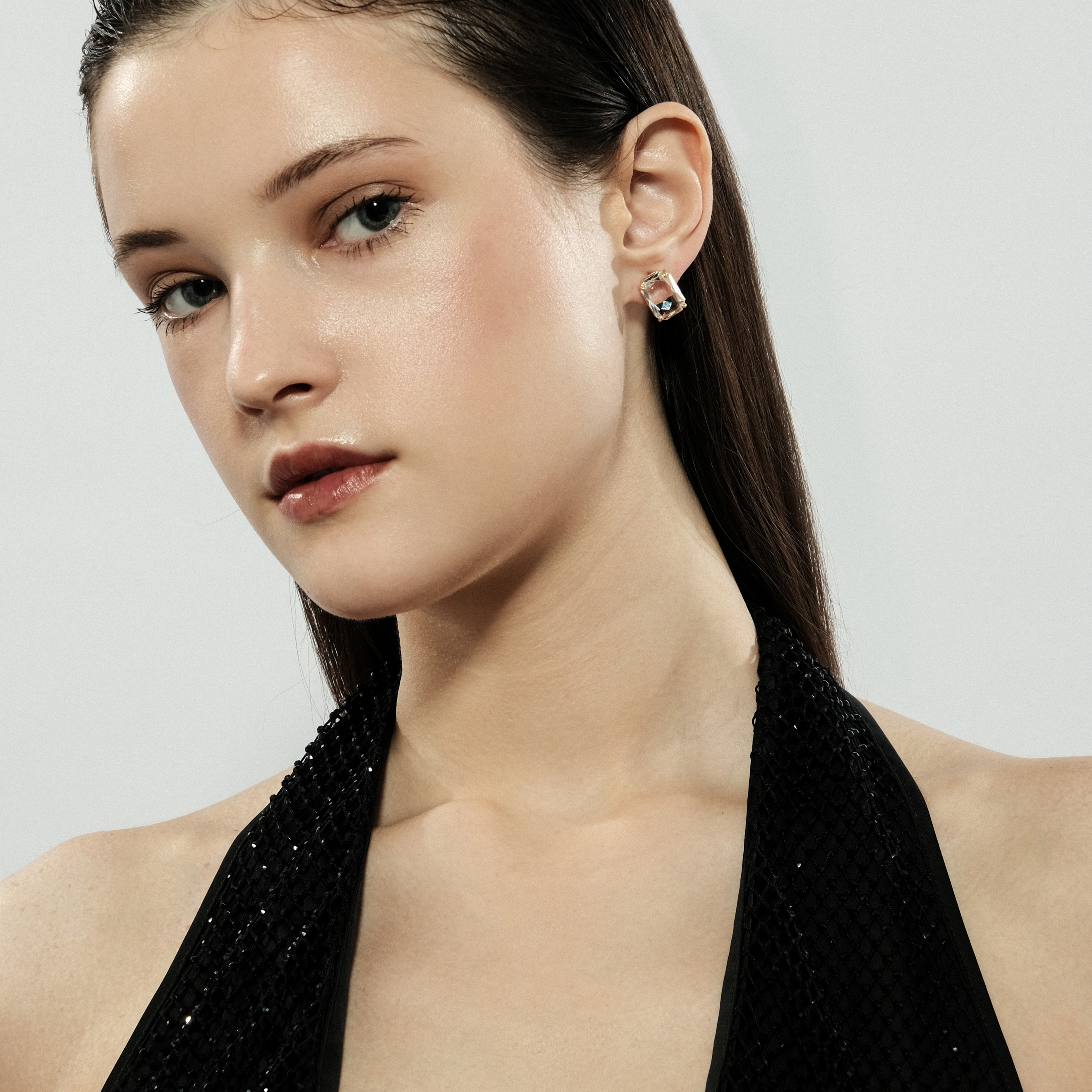 Golden stud earrings with a large white crystal