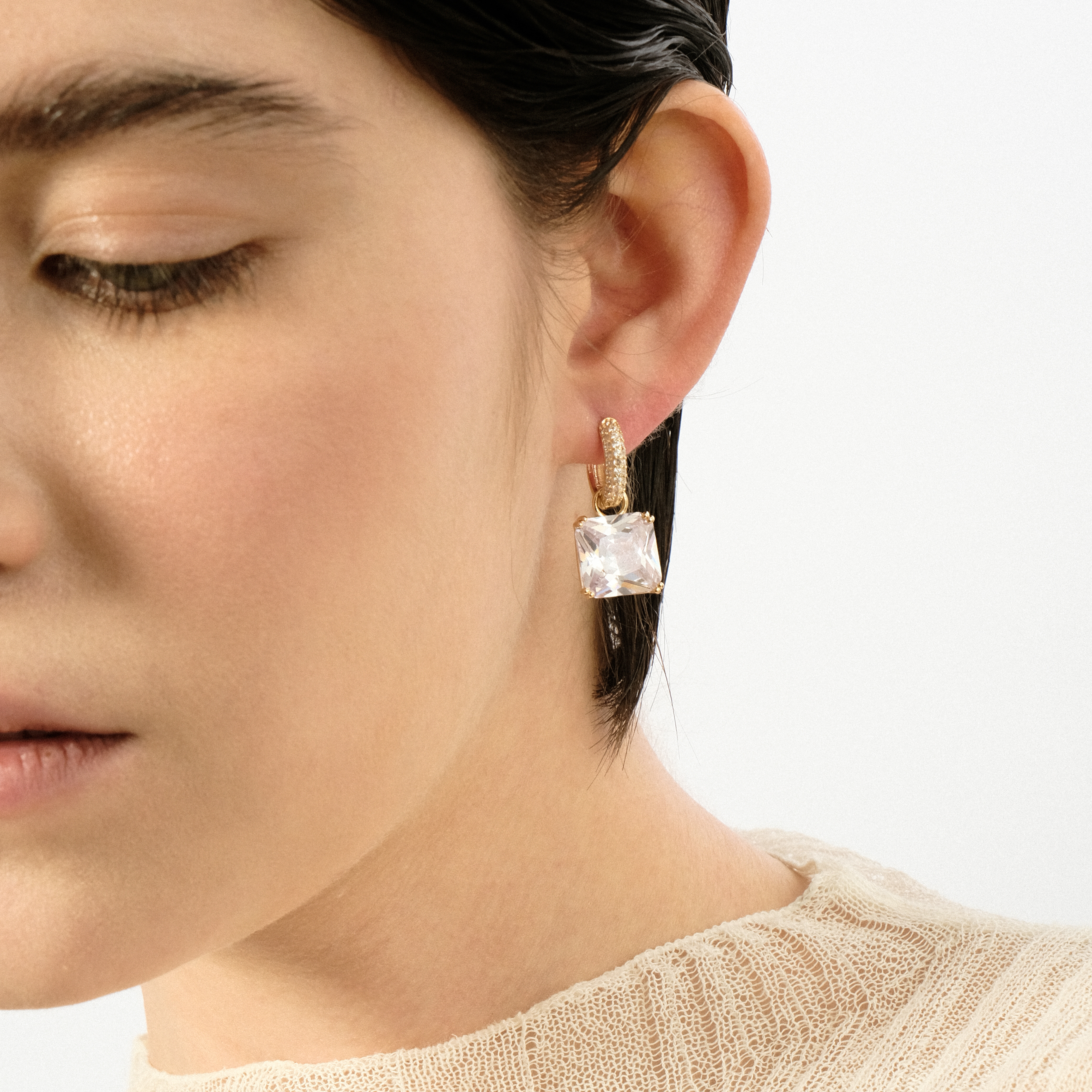 Golden earrings with a square white crystal and a peacock