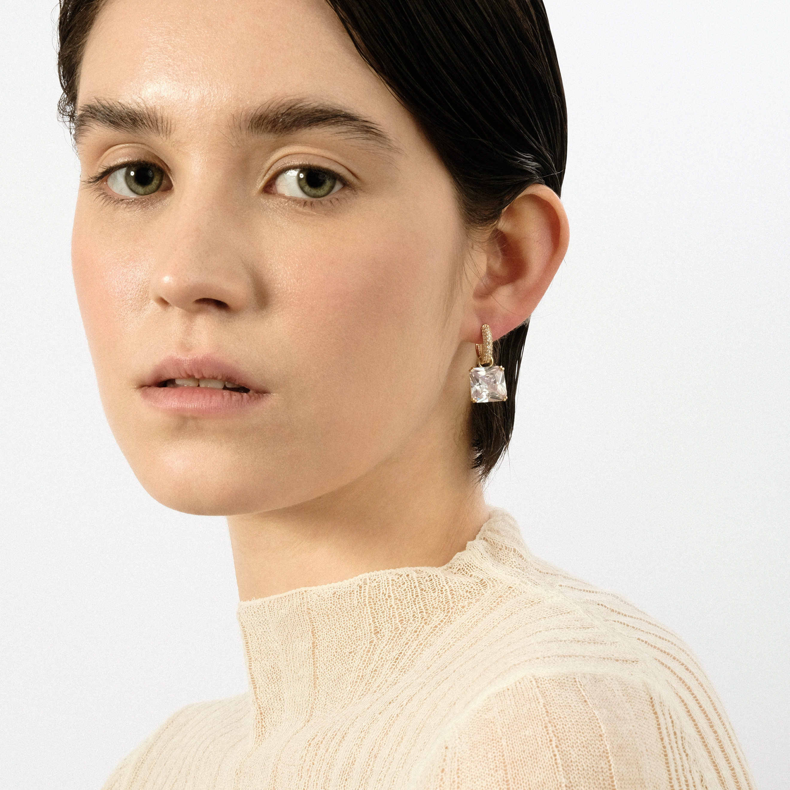 Golden earrings with a square white crystal and a peacock