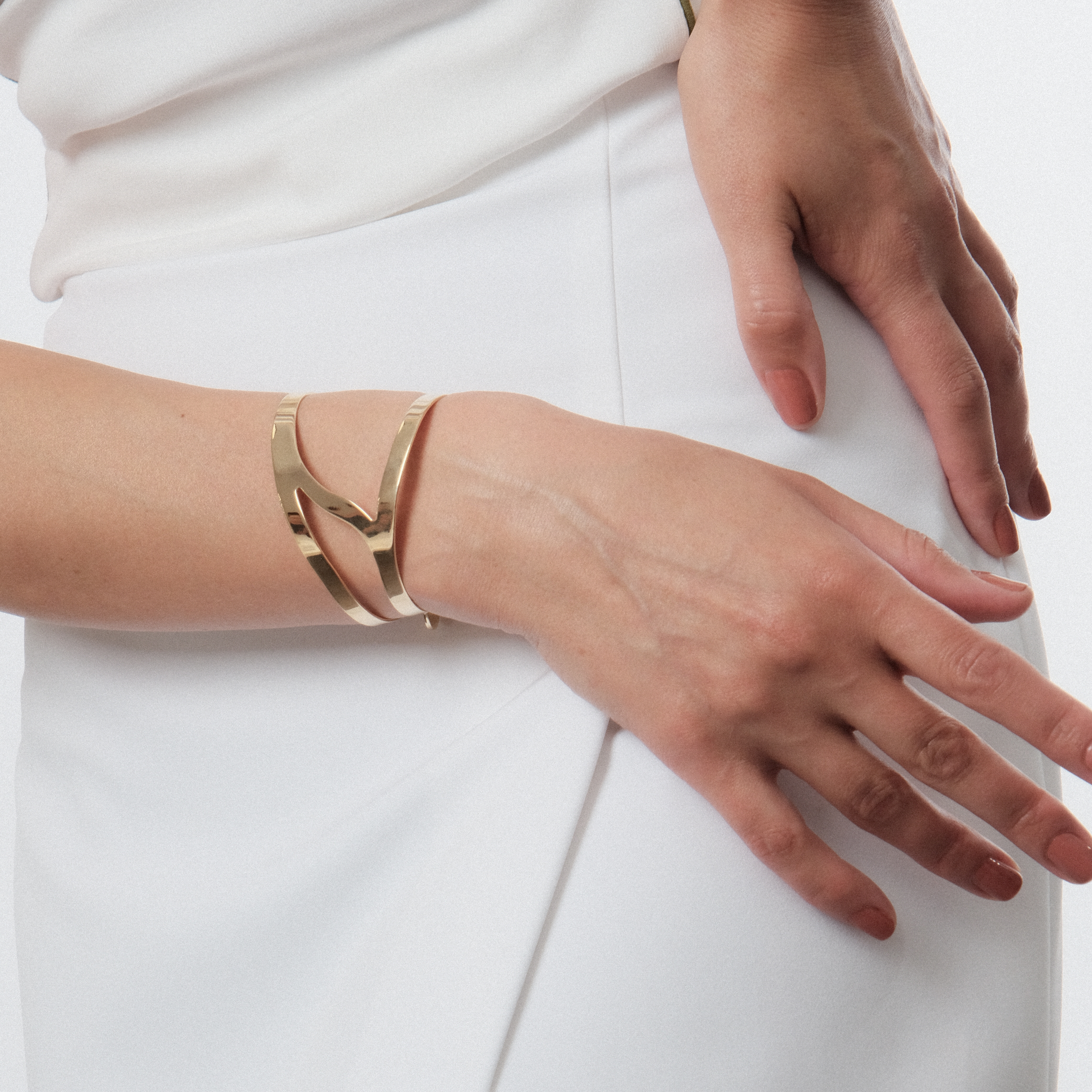 A pair of symmetrical gold-plated adjustable wrist bracelets