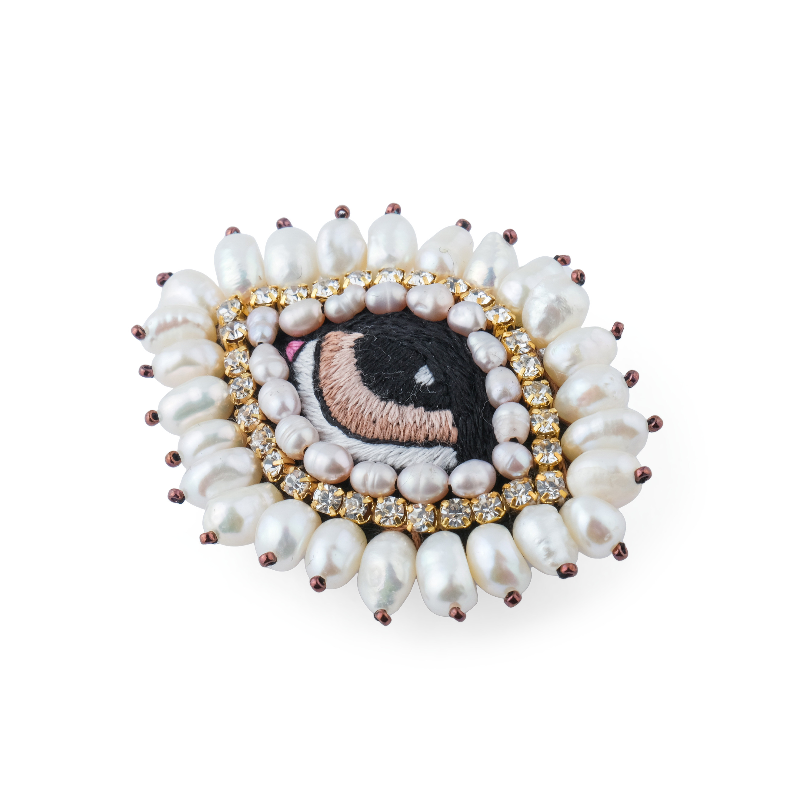 The brooch in the form of an eye is small with white pearls and a brown eye