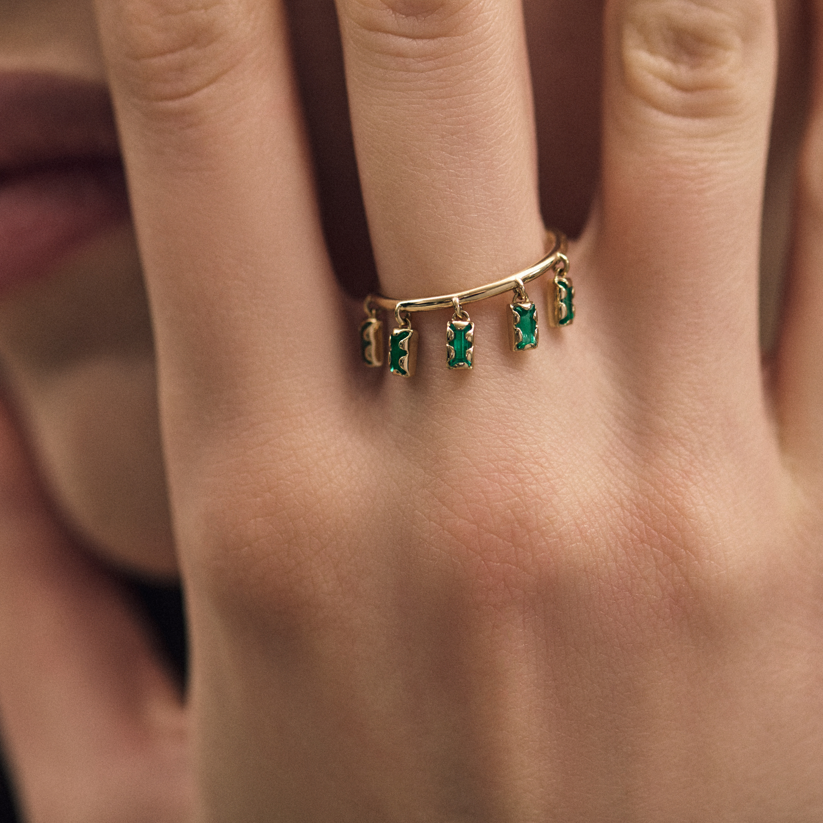 Ring with 5 hanging emeralds in an asymmetric fastening