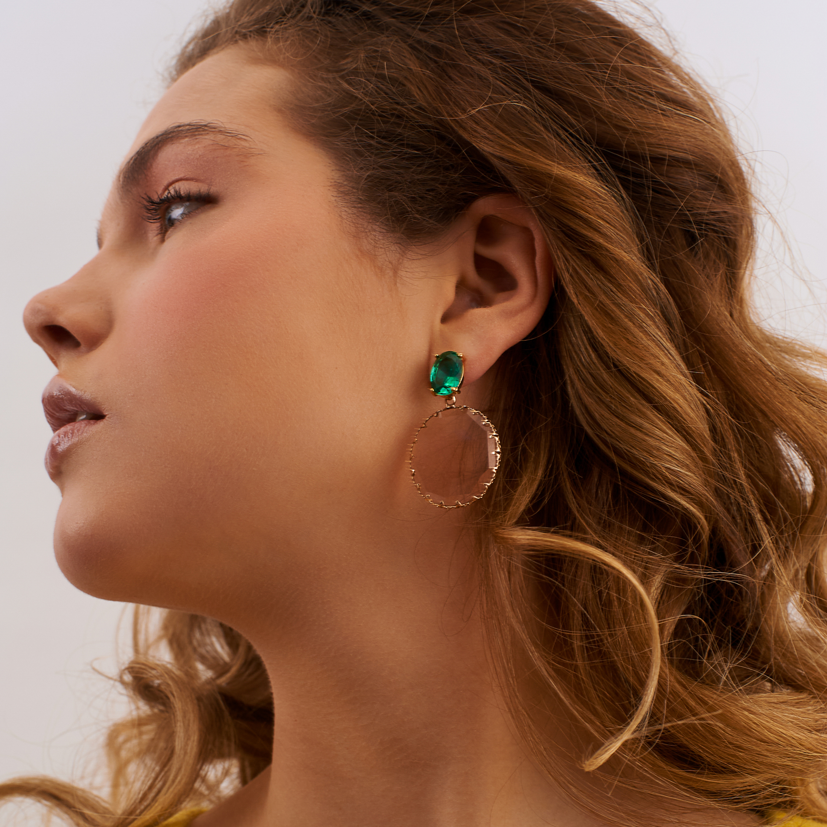 Golden earrings with large green crystals and pink oval pendants